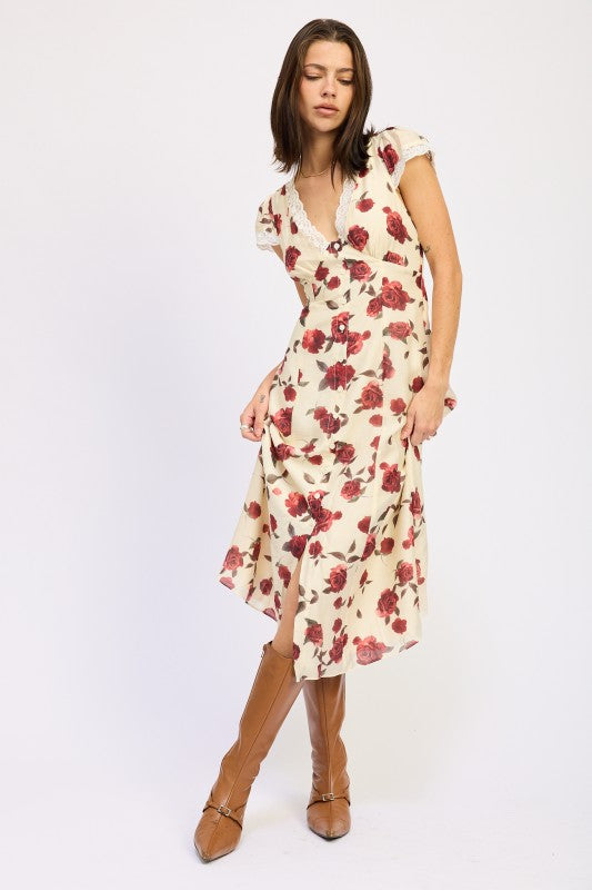 Woman models a vintage-inspired cream midi dress with red rose print, posing elegantly.