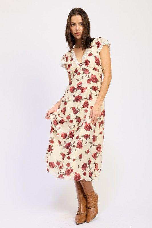 Woman models a vintage-inspired cream midi dress with red rose print, holding the dress.