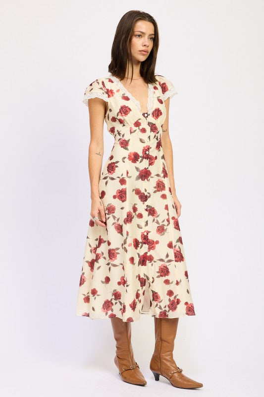 Woman models a vintage-inspired cream midi dress with red rose print, side view.