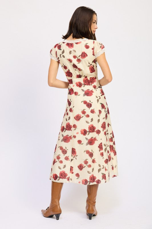 Woman models a vintage-inspired cream midi dress with red rose print, back view.