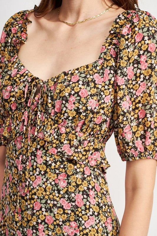 Woman models a chic floral midi dress with puff sleeves, a sweetheart neckline, and a trendy high slit, perfect for spring/summer, front close-up.