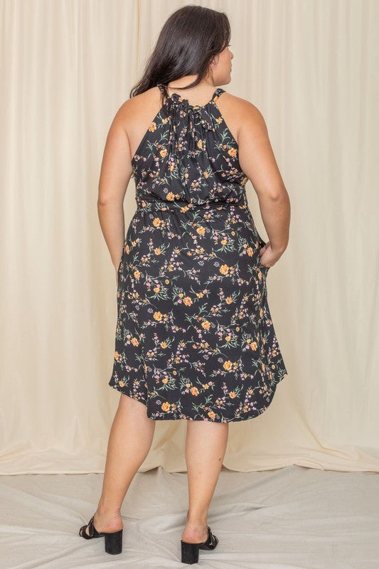 Woman wearing a floral halter neck midi dress with a flared skirt.