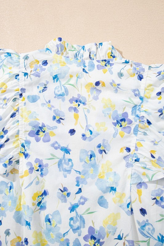 Frilled ruffle detailing at sleeves and hem enhances the blouse’s graceful flow.