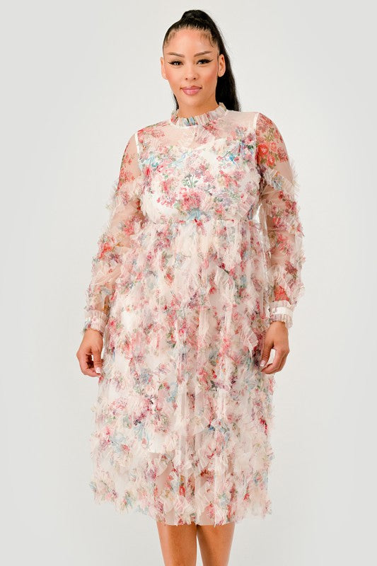 A woman wearing a Floral Ruffle Sheer Midi Dress, features an all over pastel floral print with cascading ruffle detailing for a soft, textured finish, front view.