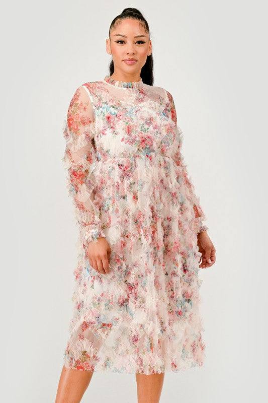 woman models an elegant floral midi dress with sheer long sleeves, a high neck, and textured ruffled details for a romantic look.