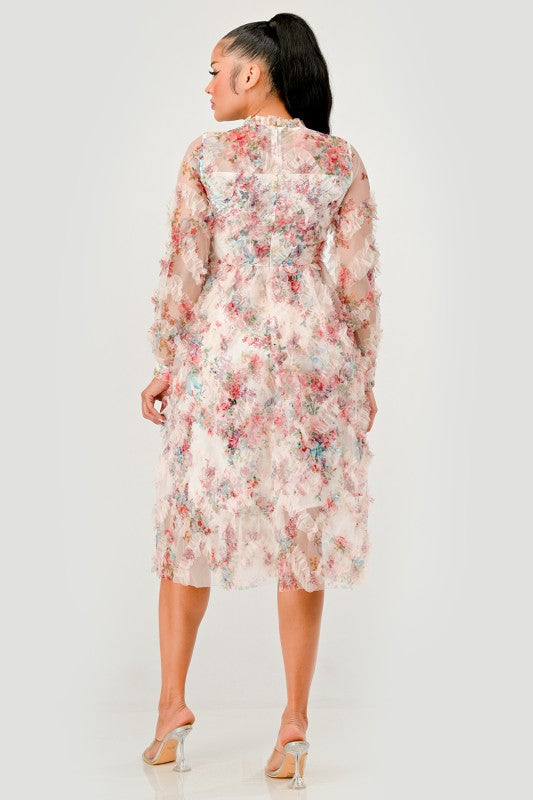 woman models an elegant floral midi dress with sheer long sleeves, a high neck, and textured ruffled details for a romantic look, back view.