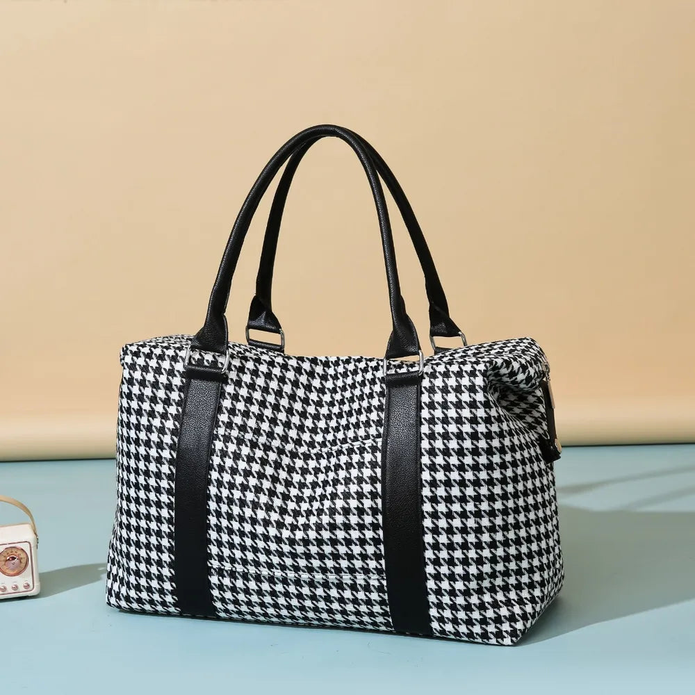 Black and white houndstooth handbag with black leather handles and accents, featuring a structured rectangular shape. Chic and modern—perfect for stylish everyday wear.
