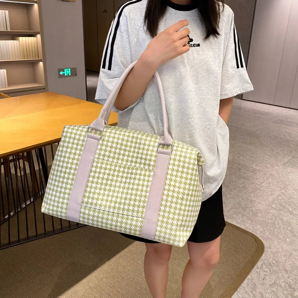 A lady holding a green and white houndstooth handbag with light beige handles and trim, placed beside stacked books. Soft, structured, and stylish—ideal for casual or semi-formal use.