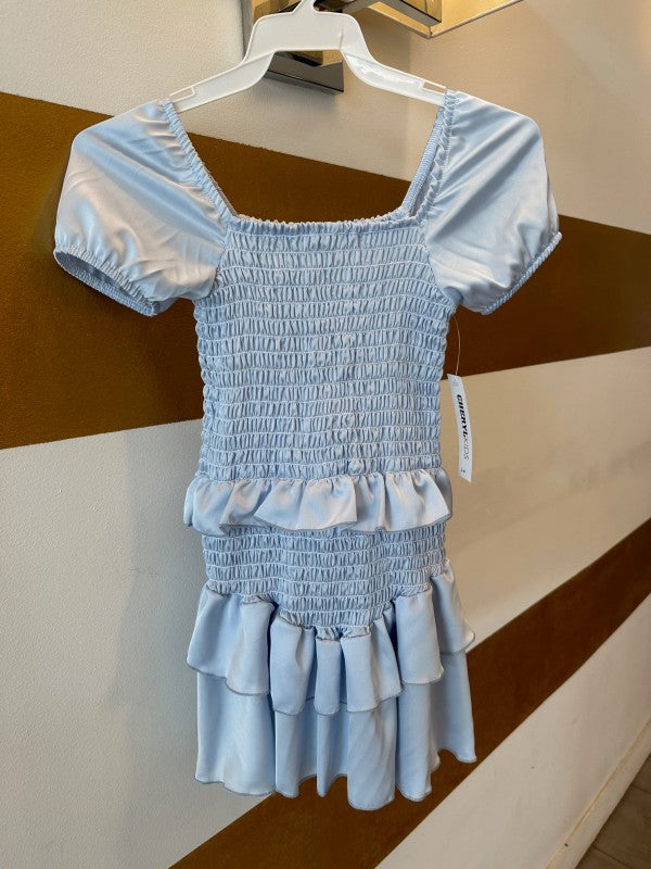 Light blue smocked dress on a hanger against a striped wall.