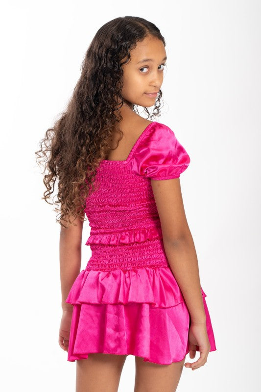 Young girl wearing a bright pink dress with puffed sleeves on a white background