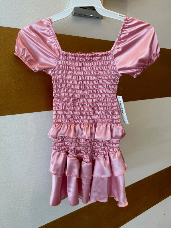 Pink smocked dress on a hanger against a striped background