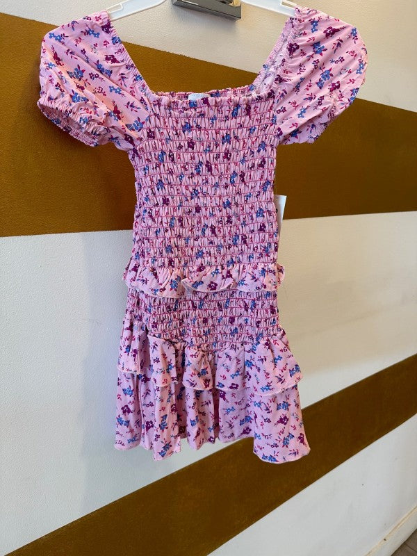 Pink floral dress on a hanger against a striped wall.