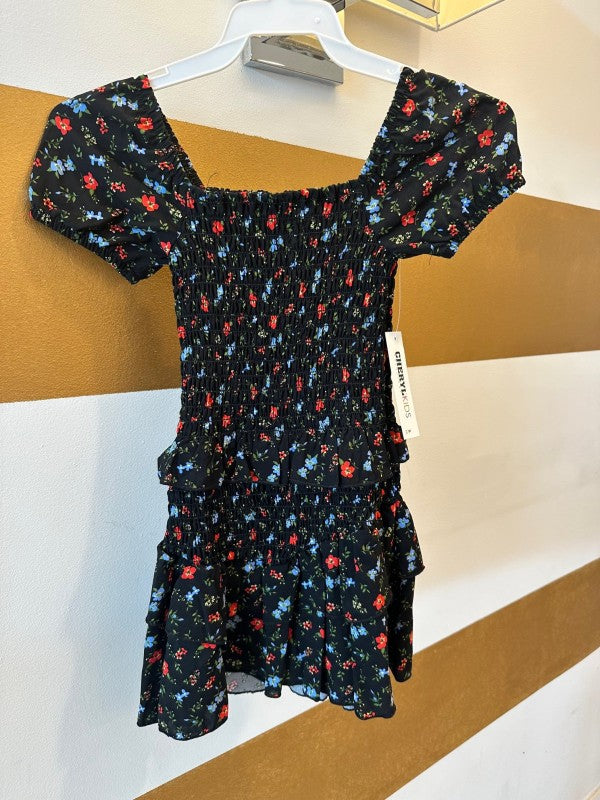 Black floral dress on a hanger against a white and brown background