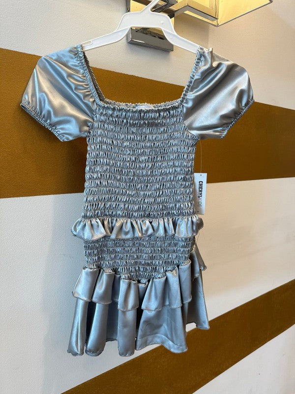 Silver dress on a hanger against a striped wall