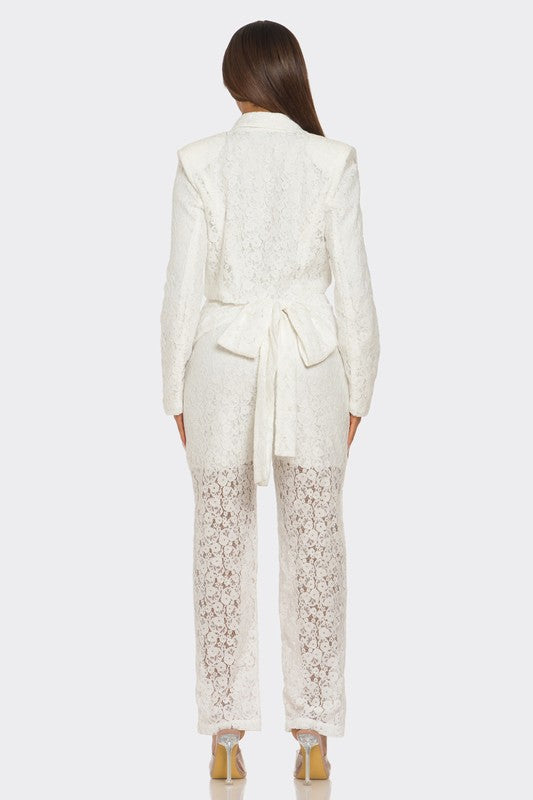 The woman is rocking a chic white suit with a plunging blazer and lace details on the pants.