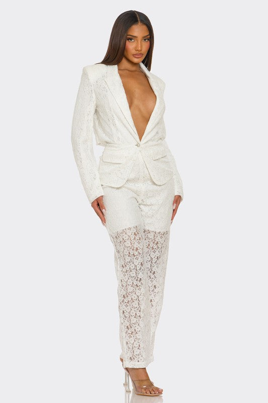 The woman is rocking a chic white suit with a plunging blazer and lace details on the pants.