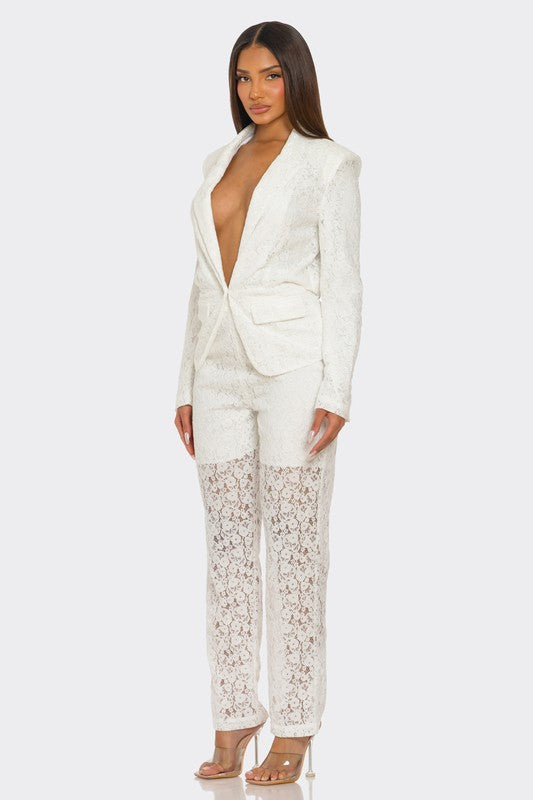 The woman is rocking a chic white suit with a plunging blazer and lace details on the pants.