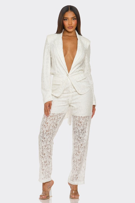 The woman is rocking a chic white suit with a plunging blazer and lace details on the pants.