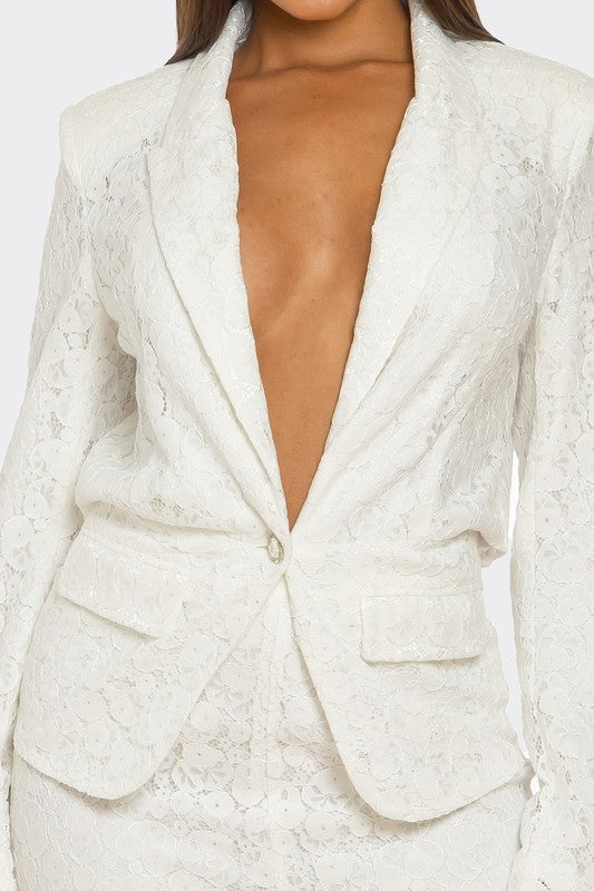 The woman is rocking a chic white suit with a plunging blazer and lace details on the pants.