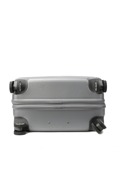 Silver hard-shell suitcase with vertical ribbed texture, extended telescopic handle, and four spinner wheels—positioned upright on a wooden floor.