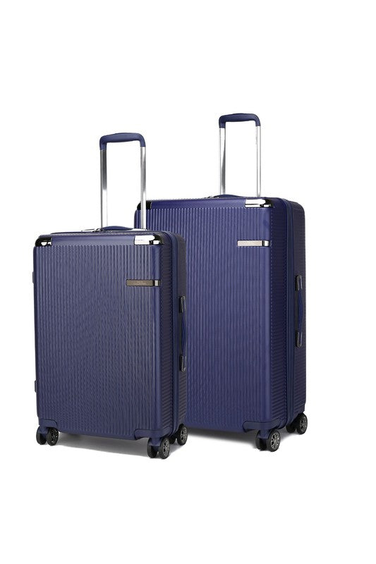 Two navy blue hard-shell suitcases with vertical texture, extended telescopic handles, and spinner wheels—standing side by side, with the left one slightly smaller than the right.