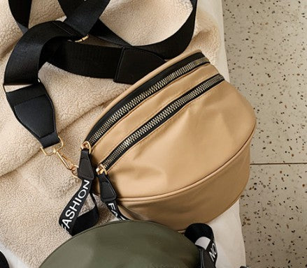 Two compact crossbody bags in beige and olive green, each with black adjustable straps, gold hardware, and “FASHION” zipper tags—stylish and functional for everyday use.