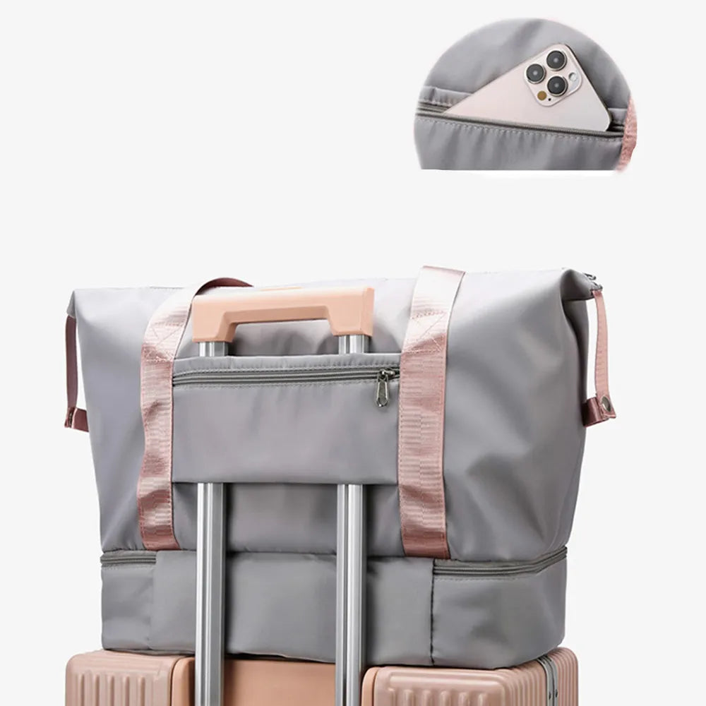 Gray and pink duffel bag with a front zip pocket, securely placed on a hard-shell suitcase. Includes a hidden phone pocket—smart and stylish for travel.