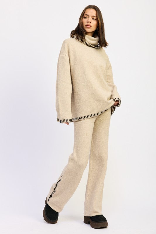 an oversized turtle neck sweater wear by a lady standing stylishly.
