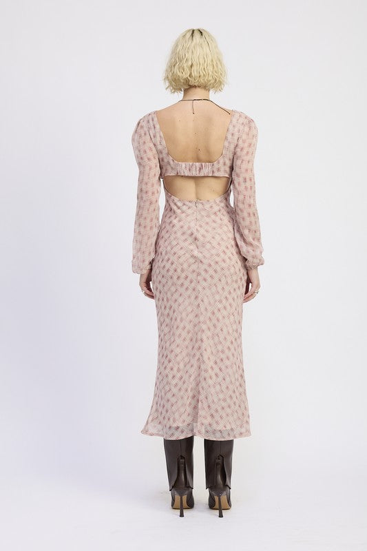 A woman with short blonde hair wearing a pink dress with a pattern and brown boots.