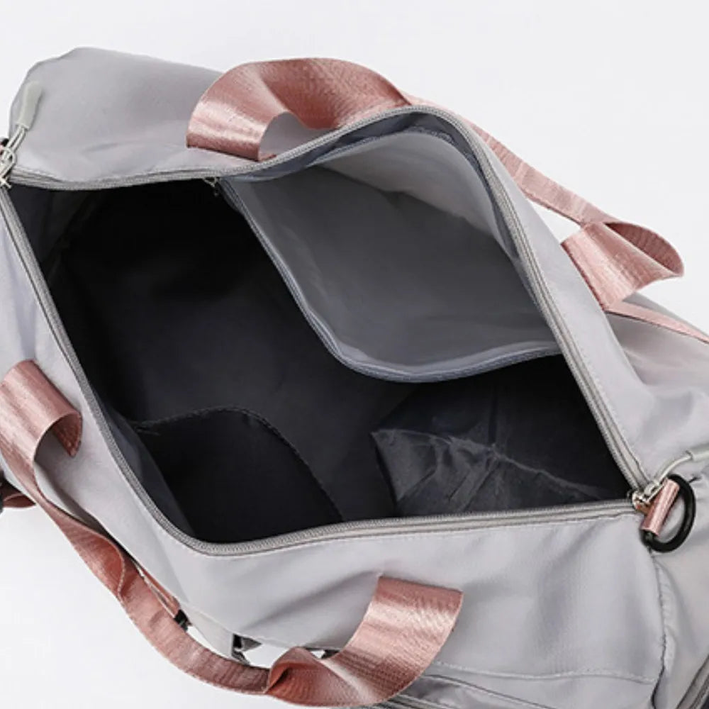 Light gray duffel bag with pink handles and shoulder strap, featuring a front zip pocket and smooth, slightly glossy material. Modern and functional—ideal for gym, travel, or everyday use.