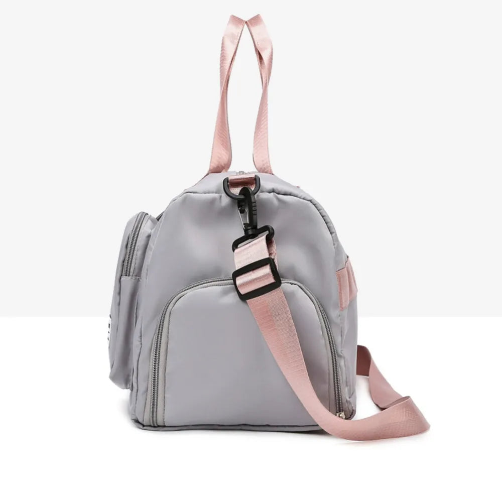Light gray duffel bag with pink handles and shoulder strap, featuring a front zip pocket and smooth, slightly glossy material. Modern and functional—ideal for gym, travel, or everyday use.