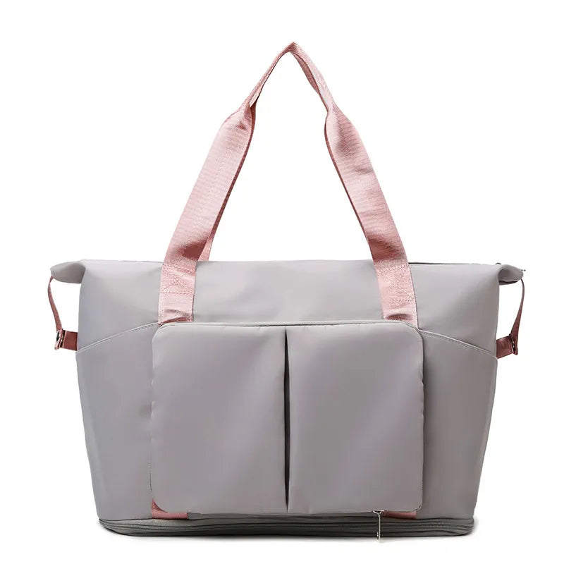 Light gray tote bag with pink handles and accents, featuring dual front pockets, a bottom zip compartment, and side loops. Durable and stylish—ideal for gym, travel, or everyday use.