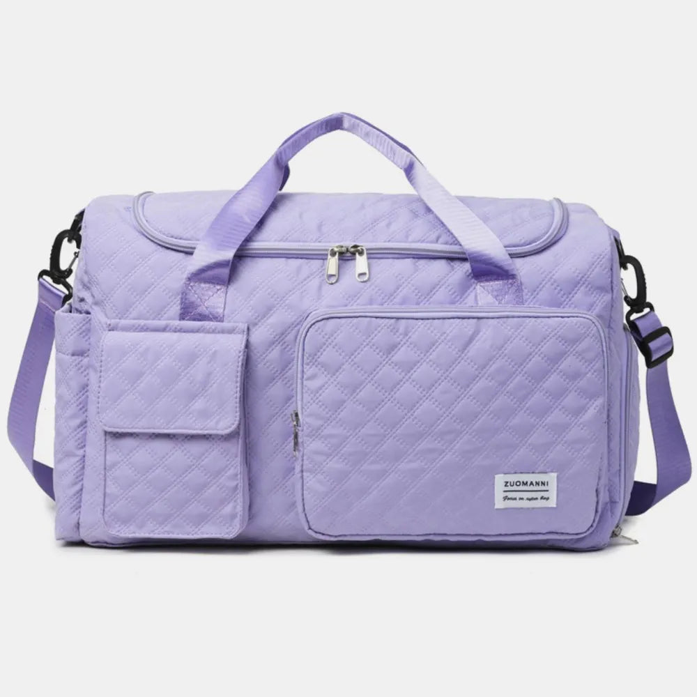 White quilted duffel bag with with short handles and an adjustable shoulder strap. Featuring a zip pocket and flap pocket on the front. Stylish and functional for travel or gym use.