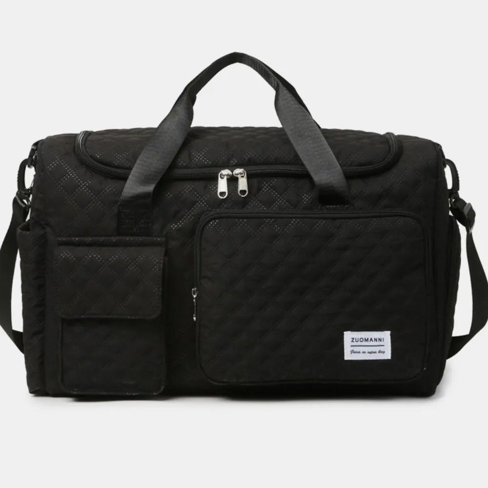 Black quilted duffel bag with black straps, featuring a zip pocket and flap pocket on the front. Stylish and functional for travel or gym use.