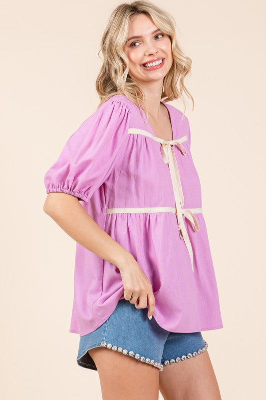 Chic V-neck babydoll top with contrast piping and gentle drape.