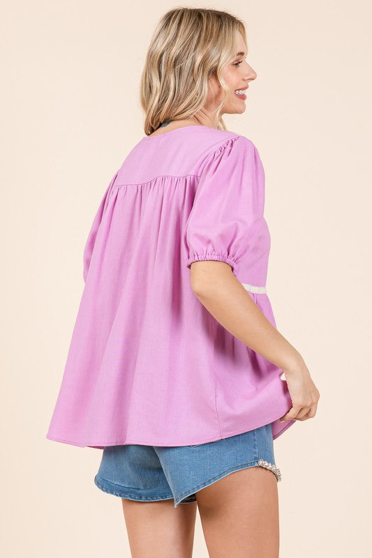 Delicate piping accents elevate this airy, loose-fit babydoll blouse.