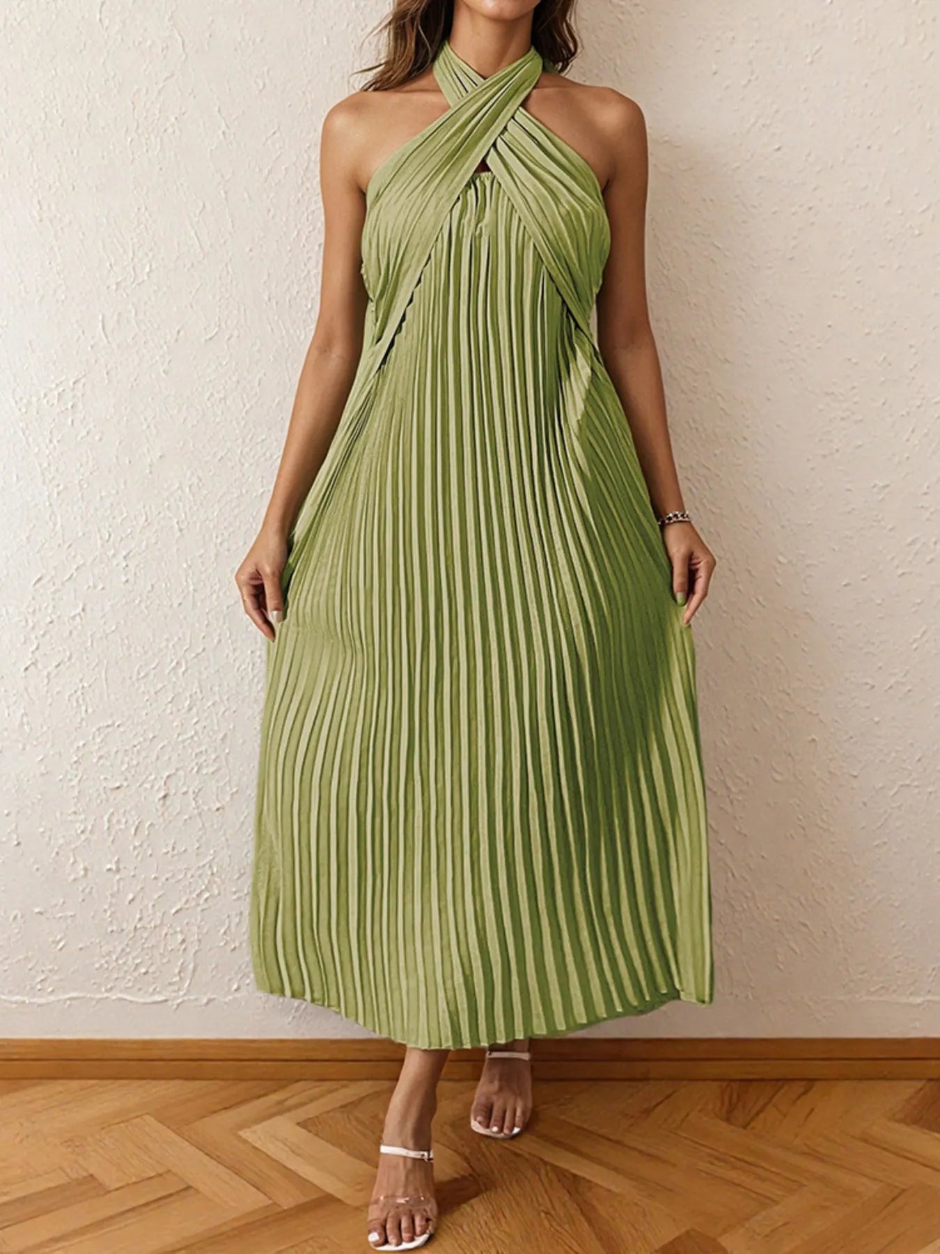 Woman wearing a pleated halter neck midi dress with crisscross neckline.