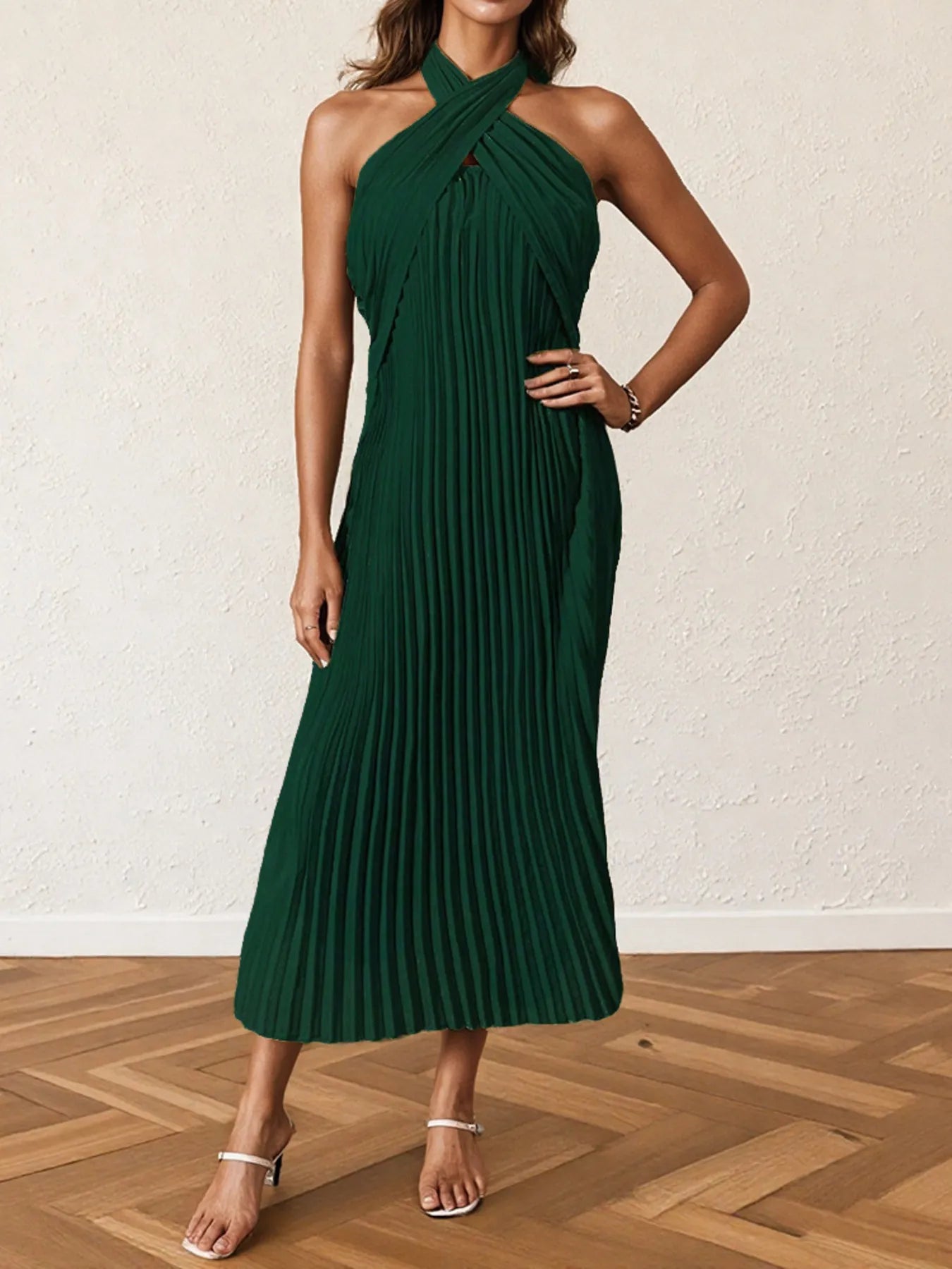 Woman wearing a pleated halter neck midi dress with crisscross neckline..