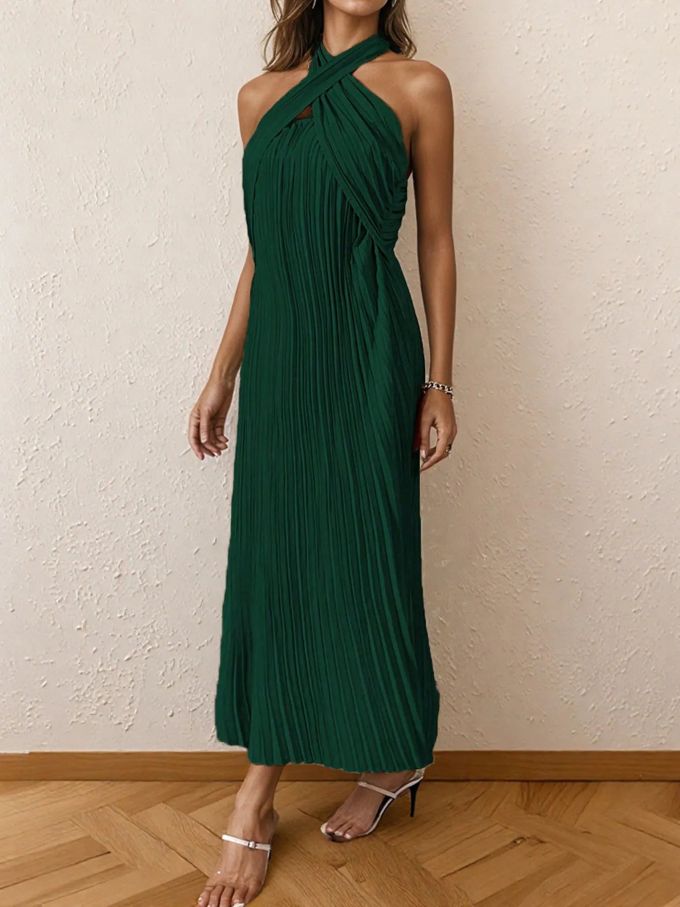 Woman wearing a pleated halter neck midi dress with crisscross neckline..