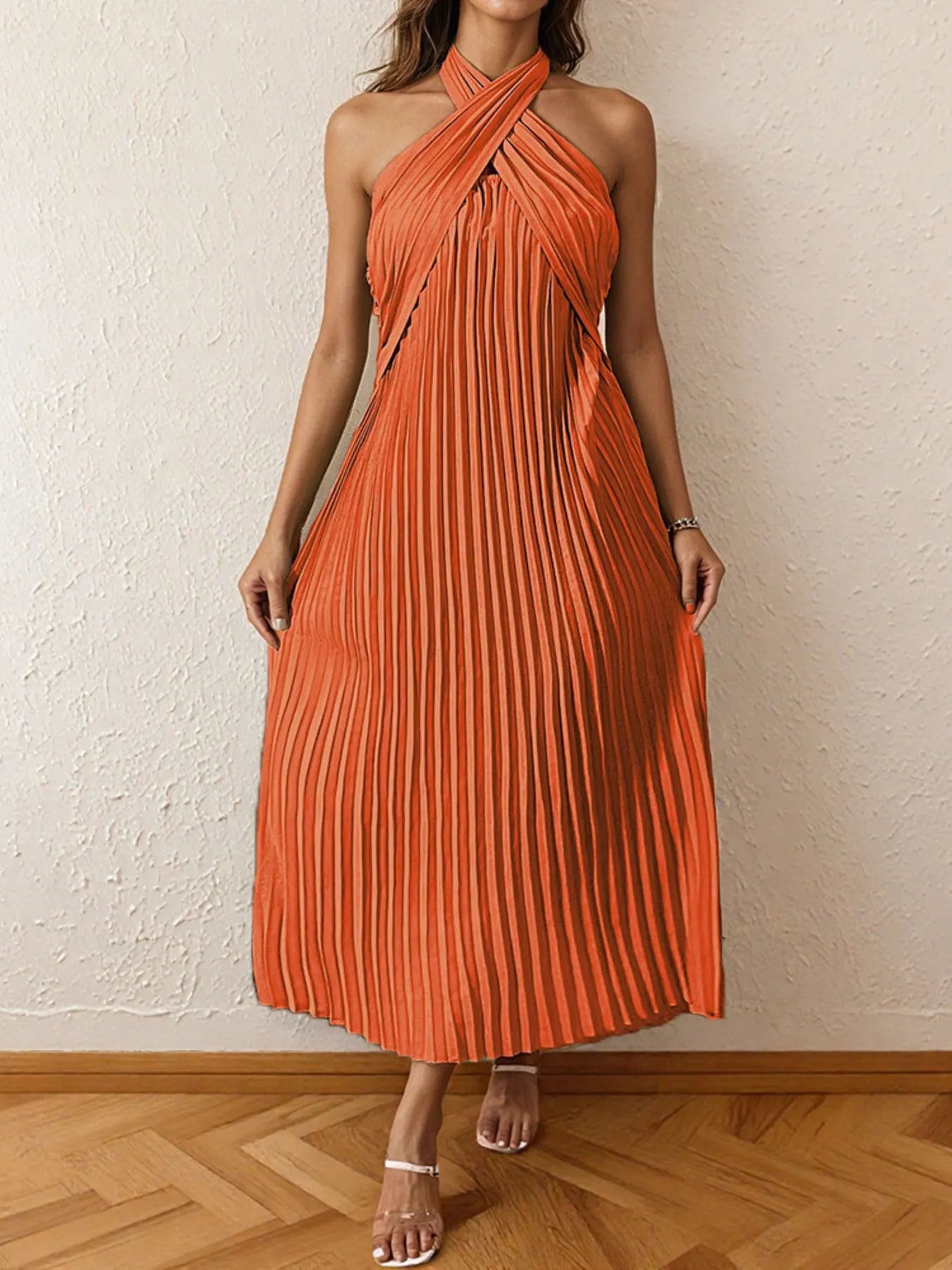 Woman wearing a pleated halter neck midi dress with crisscross neckline..