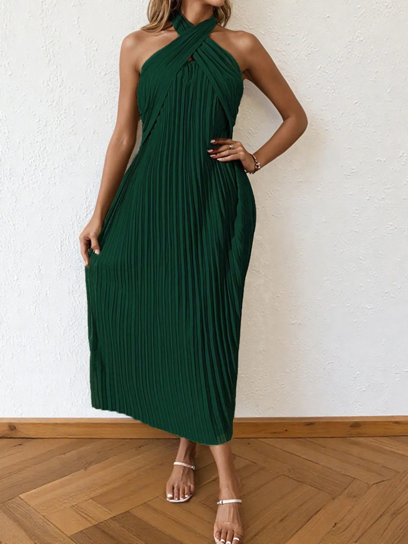 Woman wearing a pleated halter neck midi dress with crisscross neckline..