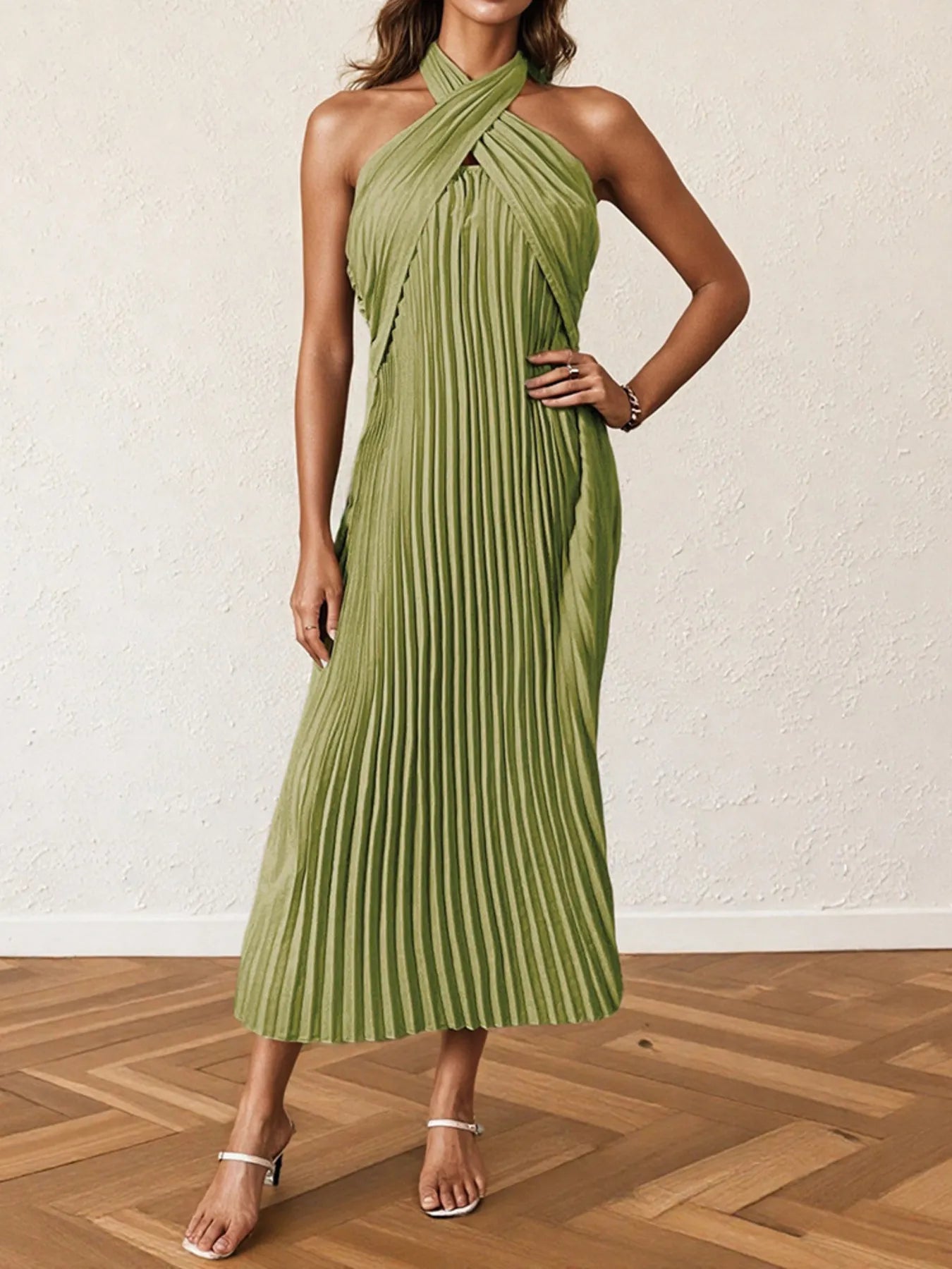 Woman wearing a pleated halter neck midi dress with crisscross neckline..