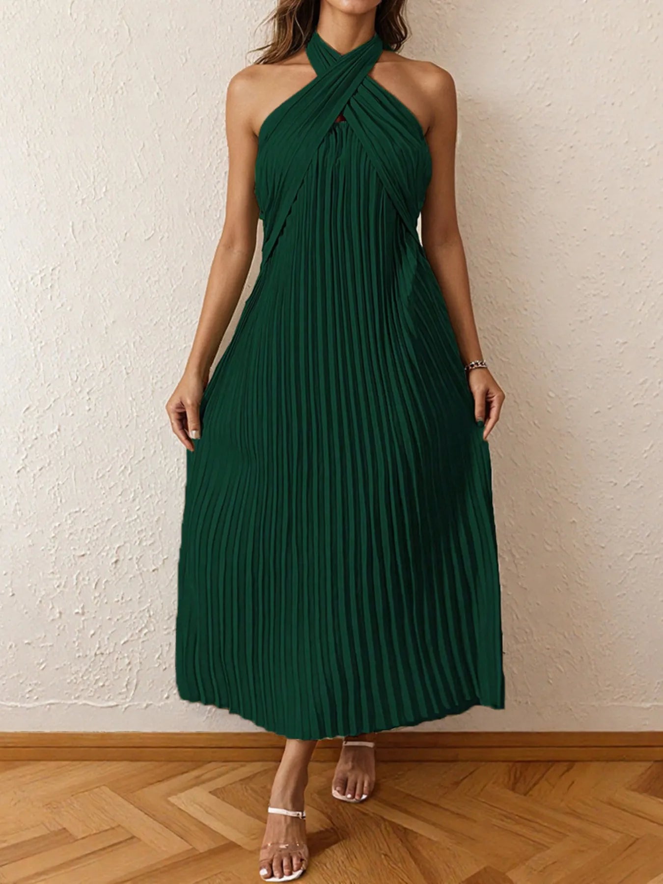 Woman wearing a pleated halter neck midi dress with crisscross neckline..