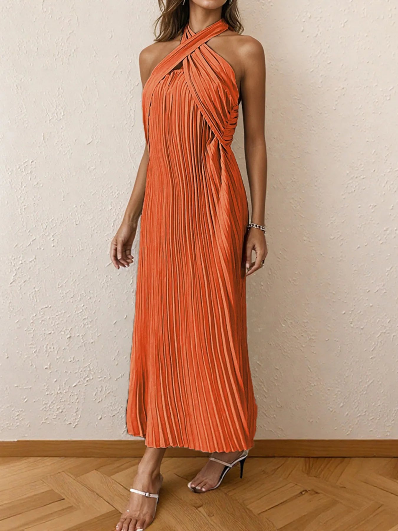 Woman wearing a pleated halter neck midi dress with crisscross neckline..