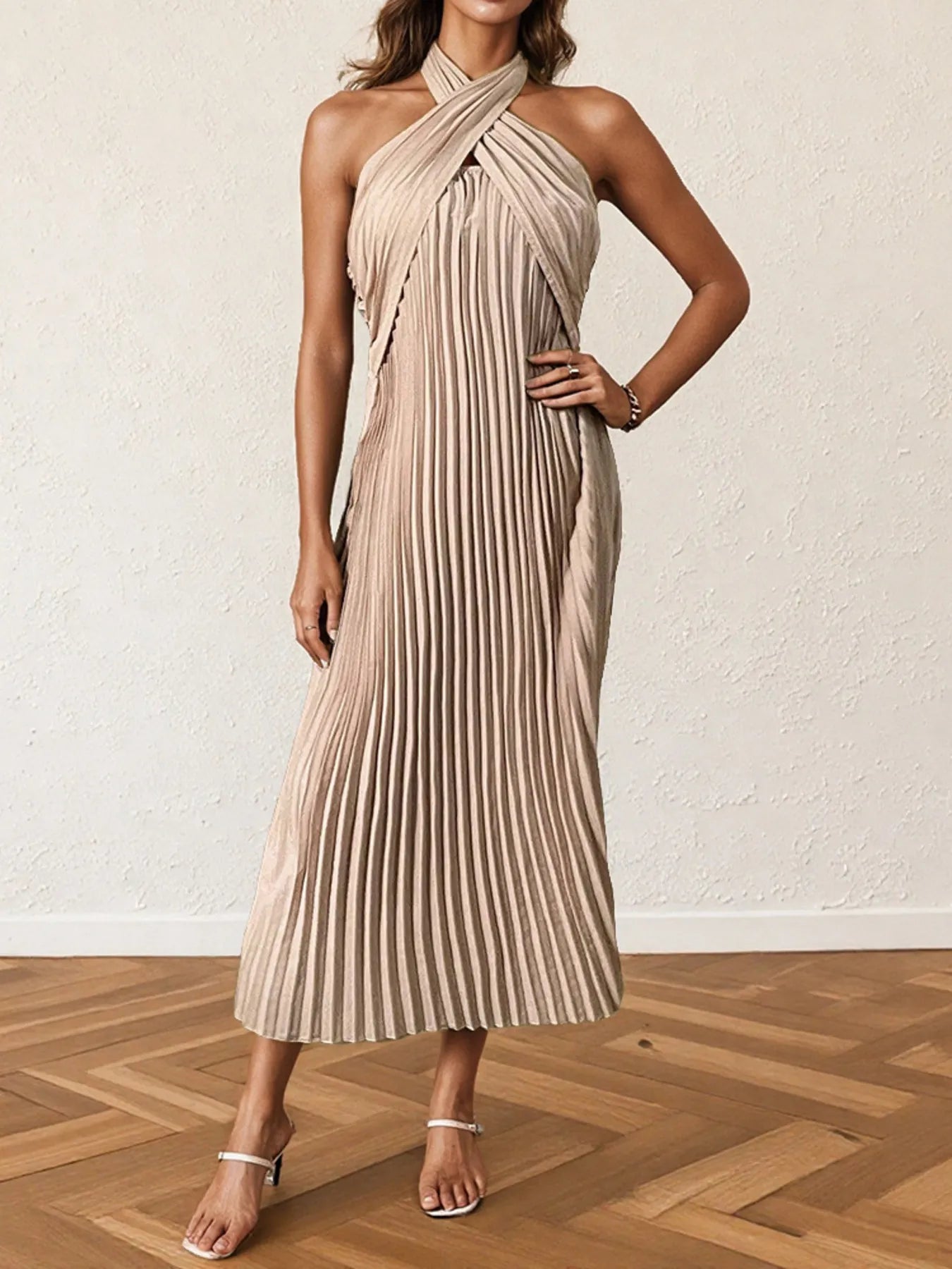 Woman wearing a pleated halter neck midi dress with crisscross neckline..