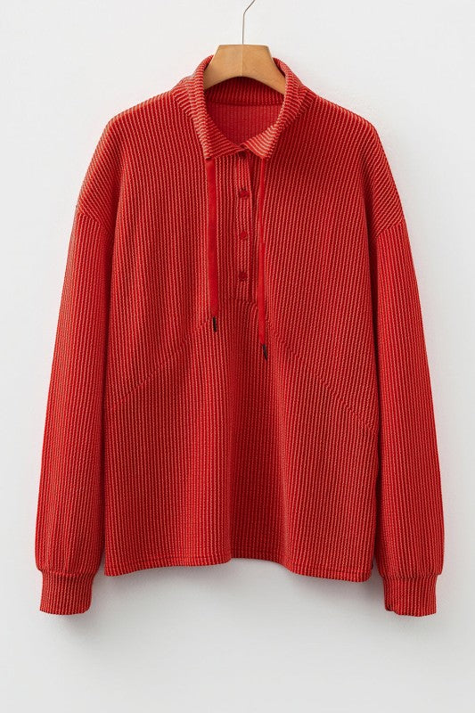 Red ribbed knit sweater with collar and button details on hanger against white background