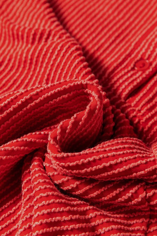 Red ribbed knit fabric texture showing detailed stitching and fold patterns