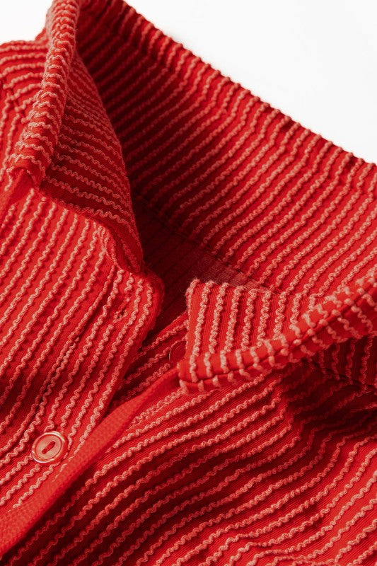 Close-up detail of red ribbed knit sweater showing collar and button texture