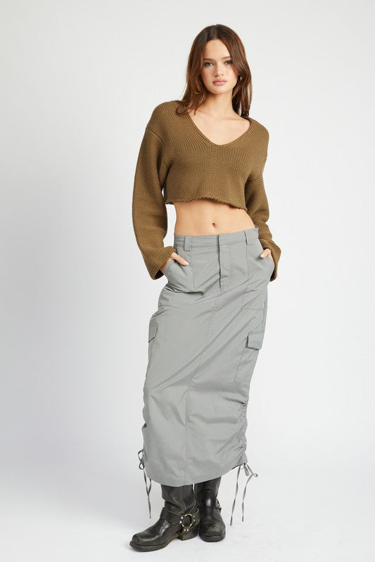 Woman wearing a brown sweater and gray skirt on a white background