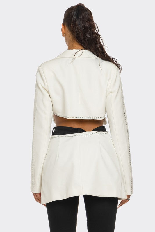 A lady rocking a cropped white jacket with a cutout at the back, paired with a matching white skirt and black leggings.